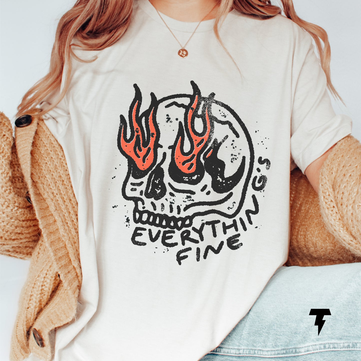 Woman wearing 'Everything is Fine' shirt with flaming skull design, styled in boho cardigan and necklace, gothic clothing vibe.