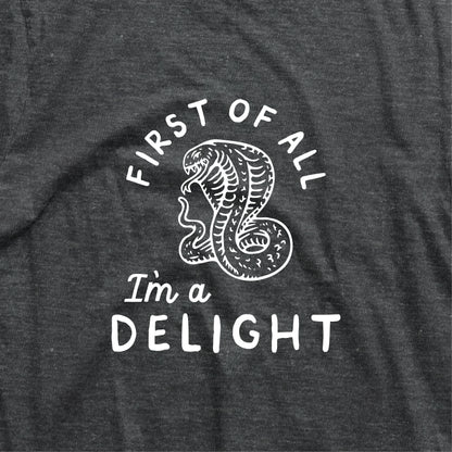 Charcoal t-shirt with 'First of all I'm a delight' and cobra graphic, witty design.