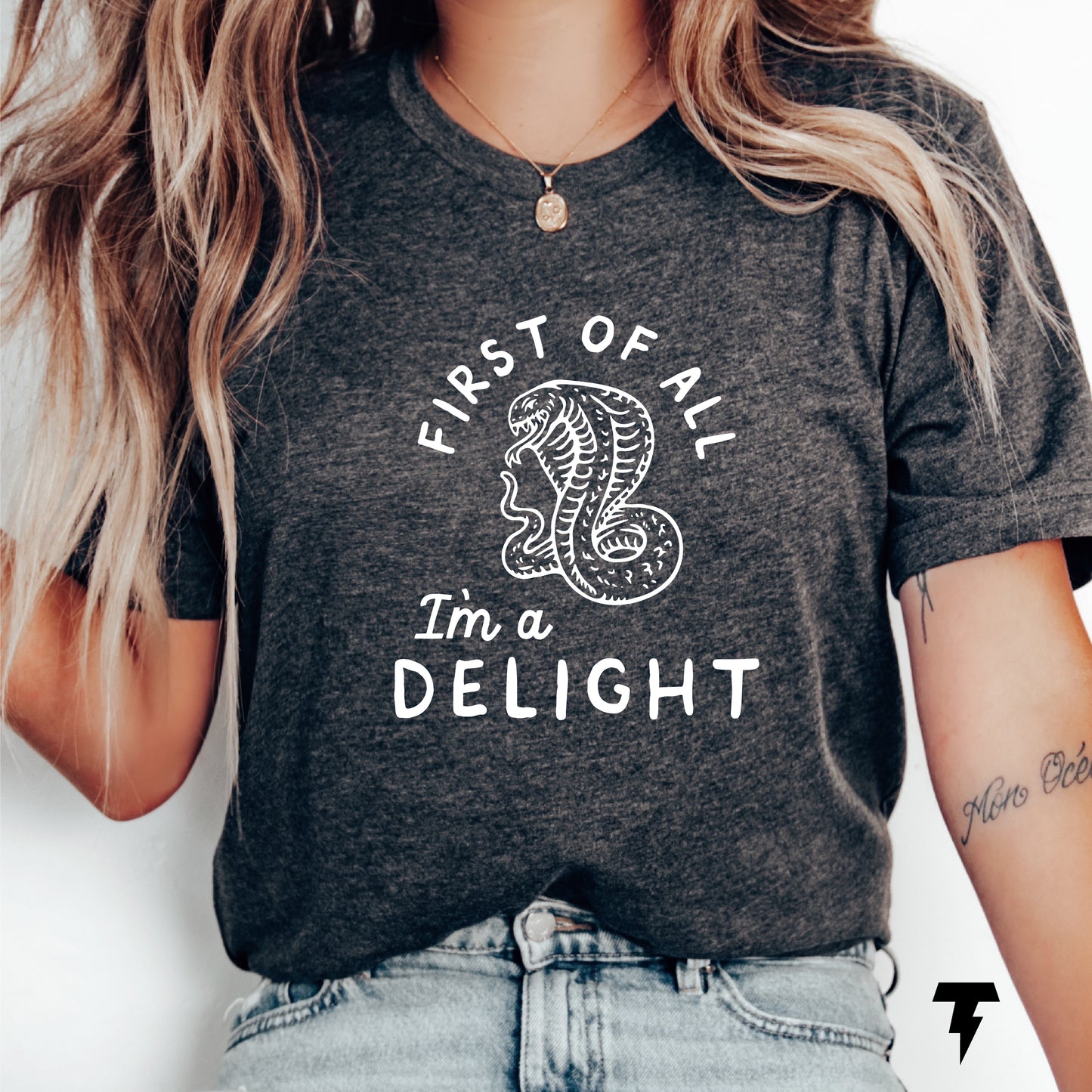 Woman wearing navy t-shirt with cobra and 'First of all I'm a delight' slogan, showcasing a funny, sarcastic style.
