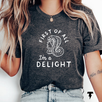 Woman wearing navy t-shirt with cobra and 'First of all I'm a delight' slogan, showcasing a funny, sarcastic style.