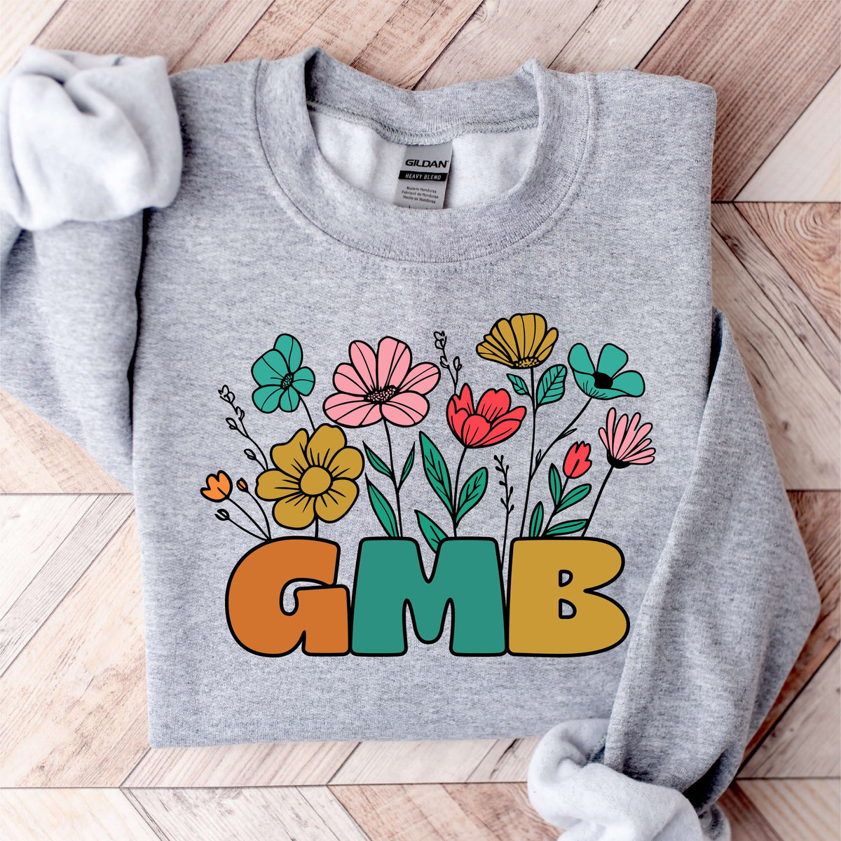 Gray sweatshirt with colorful floral design and 'GMB' text, ideal for cozy mornings and casual outings.