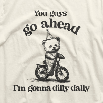 Go Ahead I Am Gonna Dilly Dally t-shirt with bear riding bike graphic and funny 90s saying, perfect for free spirits and hobbyists.