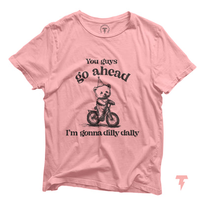 Pink T-shirt with funny bear riding a bike and 'Go Ahead I Am Gonna Dilly Dally' text, perfect for free spirits and hobbyists.