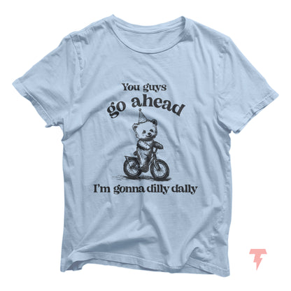 Funny bear riding bike graphic T-shirt with 'Go Ahead I'm Gonna Dilly Dally' sayings in light blue. Perfect for free spirit enthusiasts.