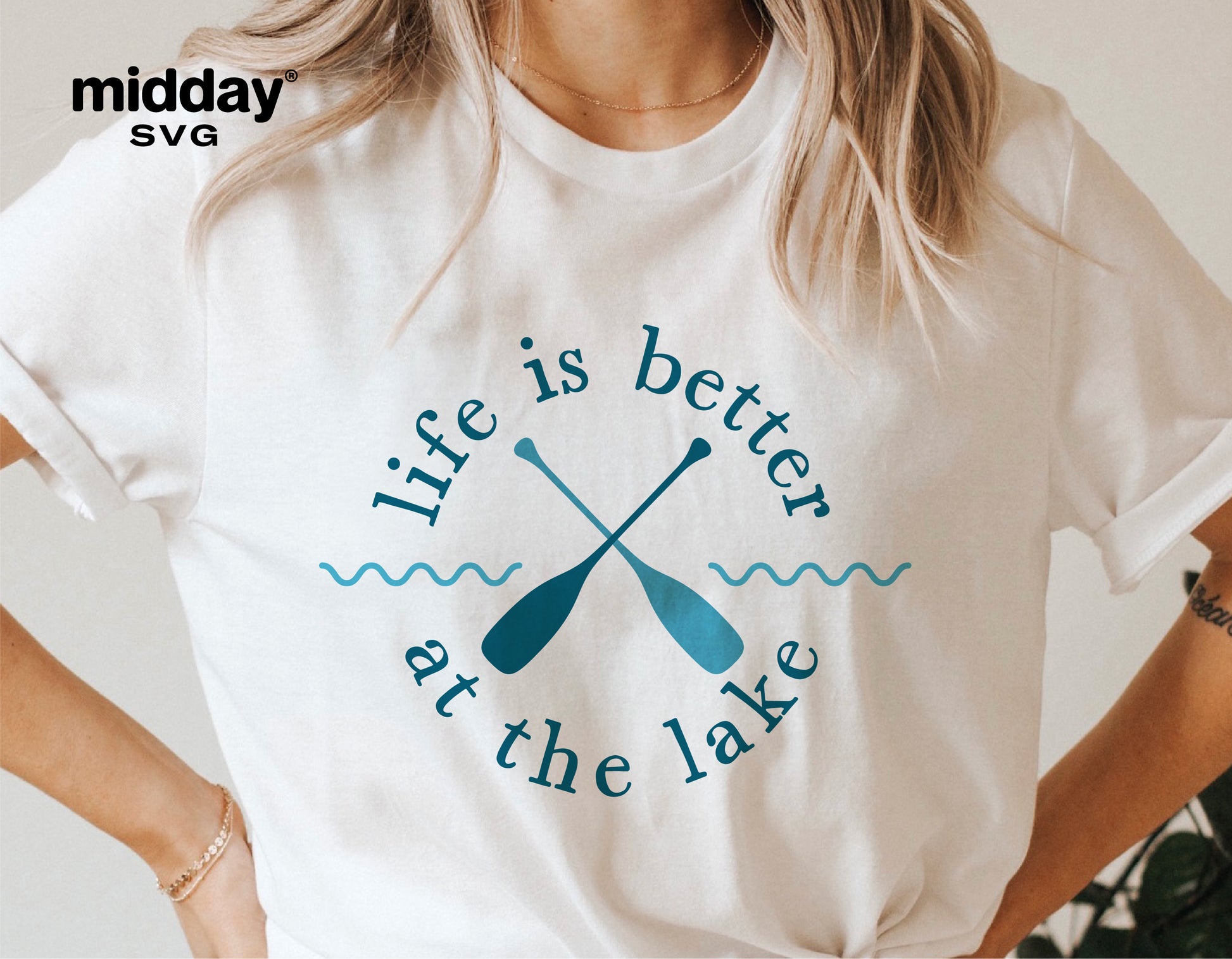 Woman wearing a white t-shirt with 'Life is better at the lake' design featuring crossed paddles; ideal for lake-themed decor.
