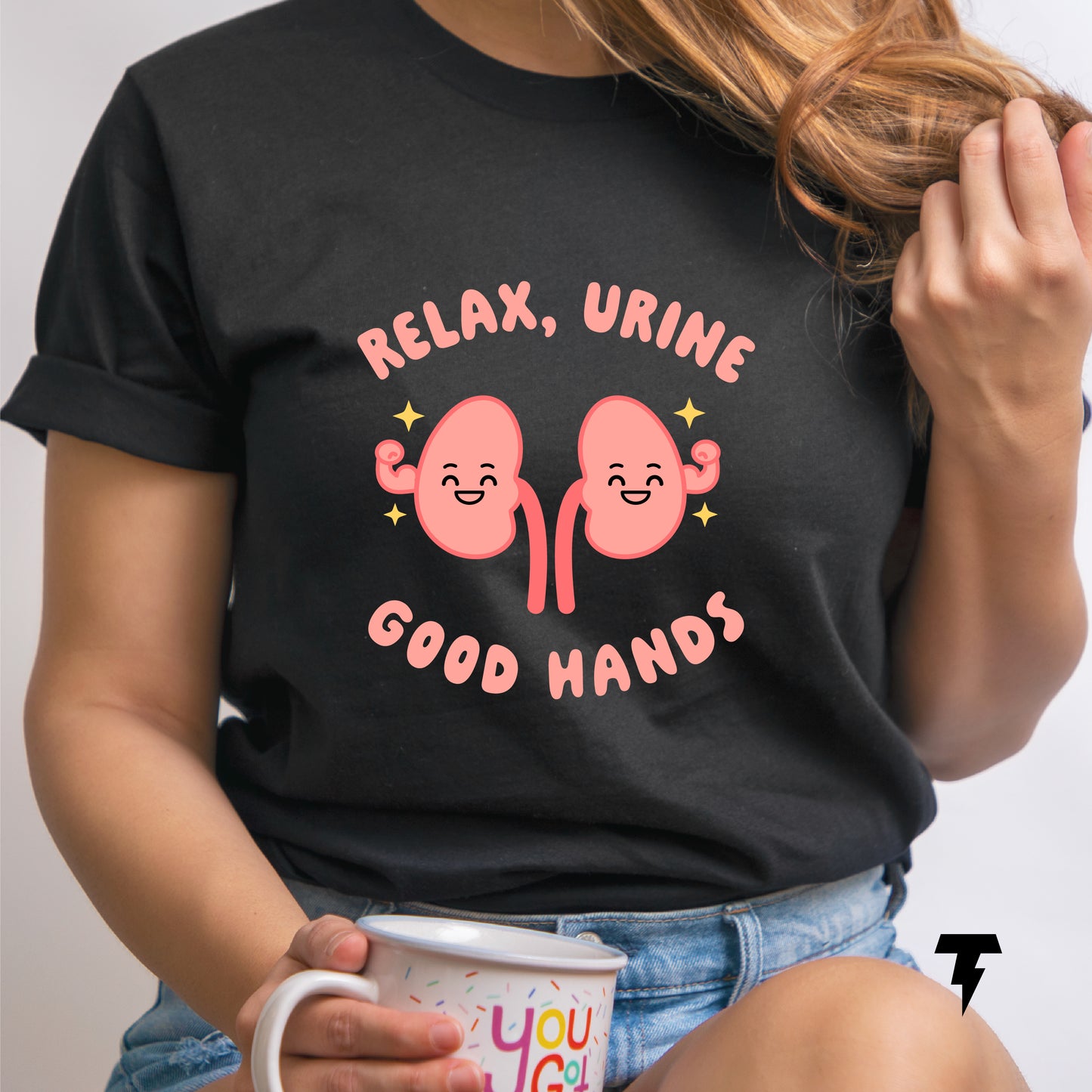 Woman wearing black "Relax, Urine Good Hands" kidney-themed shirt, holding a coffee mug.