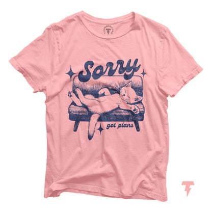 Pink cat shirt with 'Sorry, got plans' text, featuring a cat lounging on a sofa. Ideal gift for cat lovers and introverts.