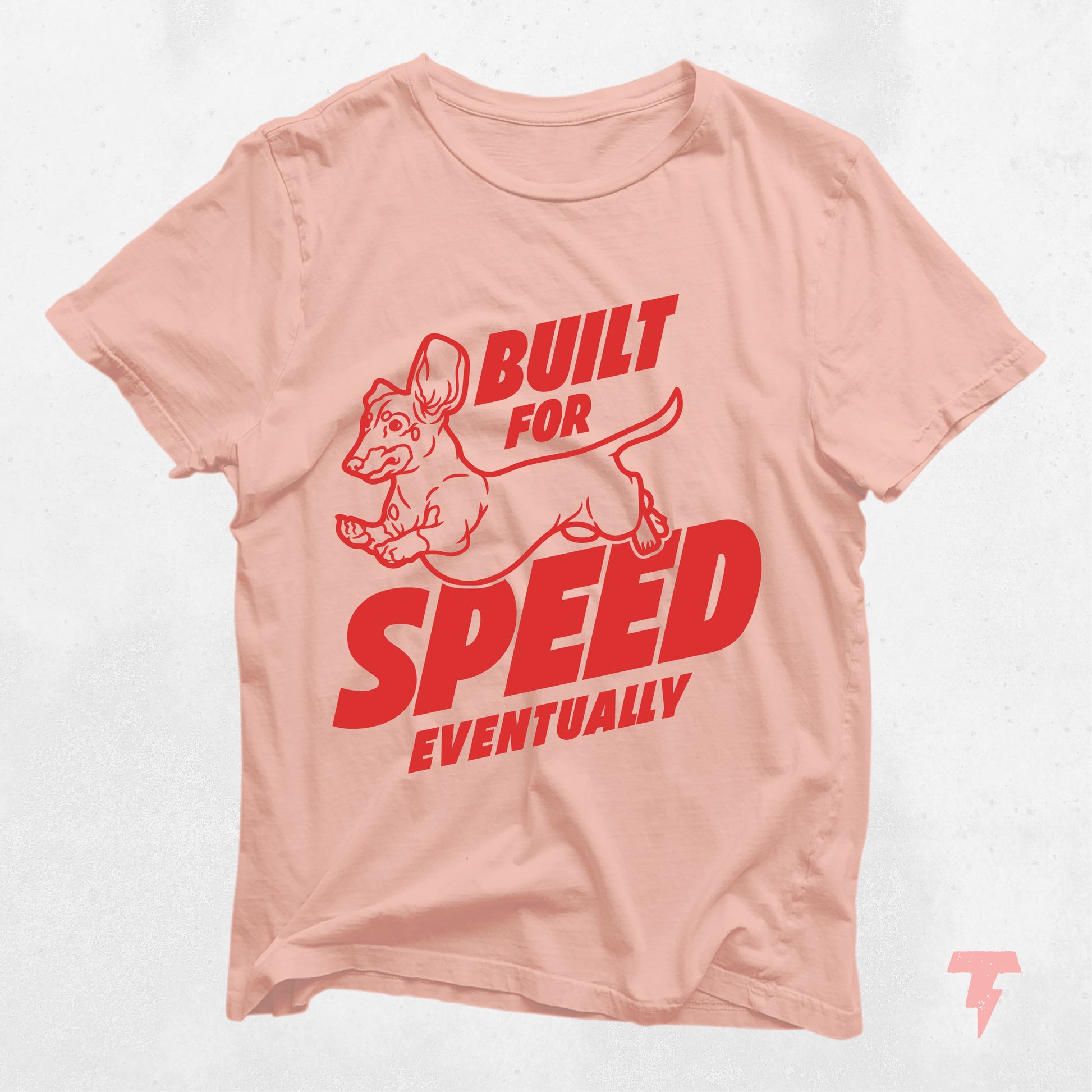 "Built for Speed Eventually" dachshund shirt in light pink with red text, cute gift for dog moms.