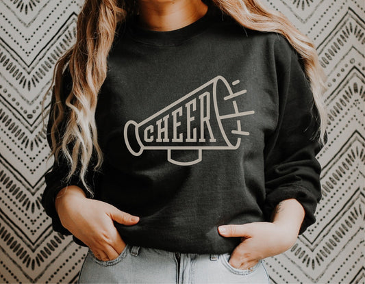 Woman wearing black sweatshirt with megaphone cheerleader SVG design, ideal for Cricut projects and cheerleading merchandise.