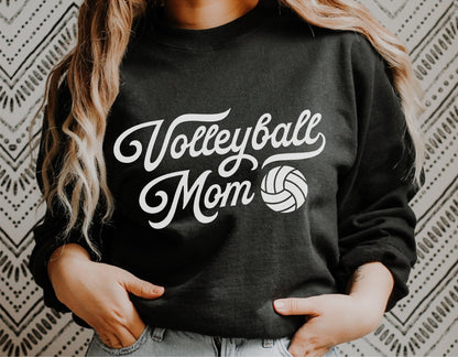 Woman wearing a black sweatshirt with 'Volleyball Mom' design, featuring vintage lettering and a volleyball graphic.