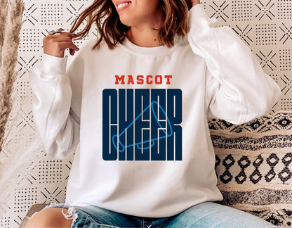 Woman wearing 'Mascot Cheer' sweatshirt with graphic design, sitting on a couch.