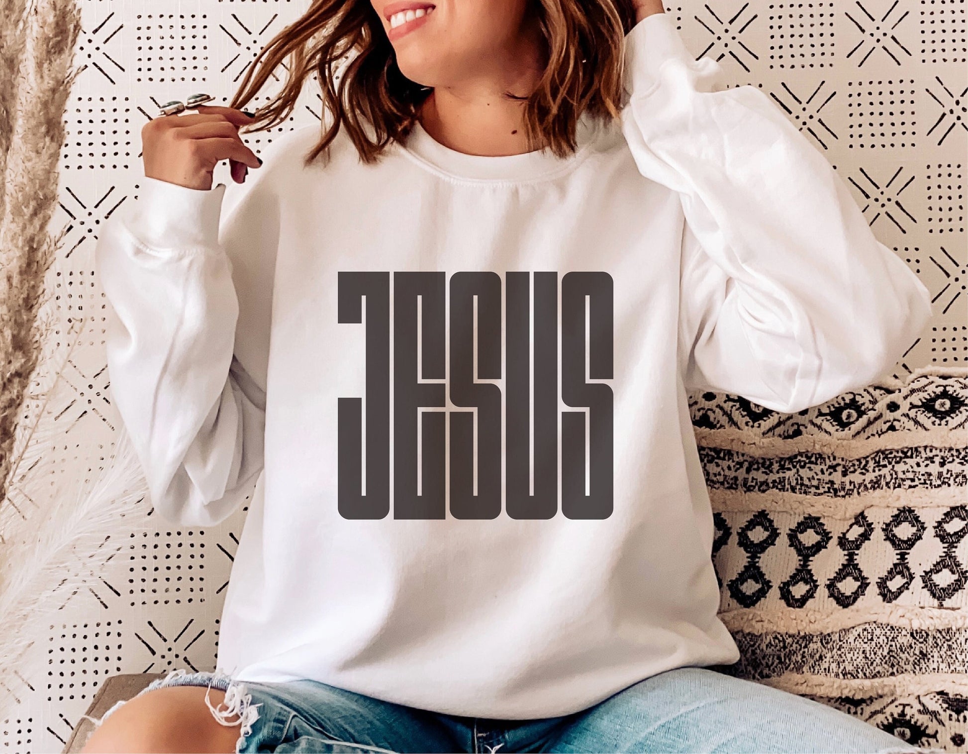 Woman wearing a white sweatshirt with bold 'JESUS' print, showcasing Christian faith and casual style.