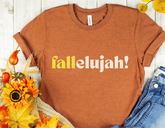 Rust-colored t-shirt with 'Fallelujah!' text, surrounded by autumn decor including pumpkins, sunflowers, and fall leaves.