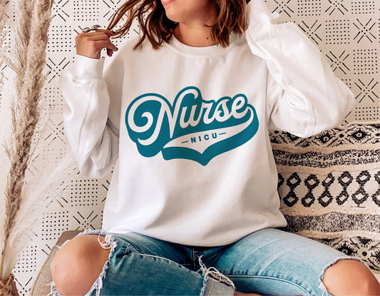 Woman wearing white sweatshirt with teal 'NICU Nurse' design, sitting on textured cushion. Ideal for nurse-themed SVG projects.