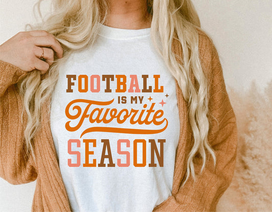 White t-shirt with 'Football is My Favorite Season' design in orange and brown, worn by person with long blonde hair.