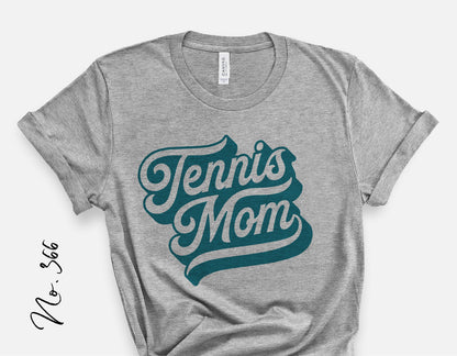Heather gray shirt with 'Tennis Mom' graphic in teal lettering, perfect for sporty tennis fans and mom enthusiasts.