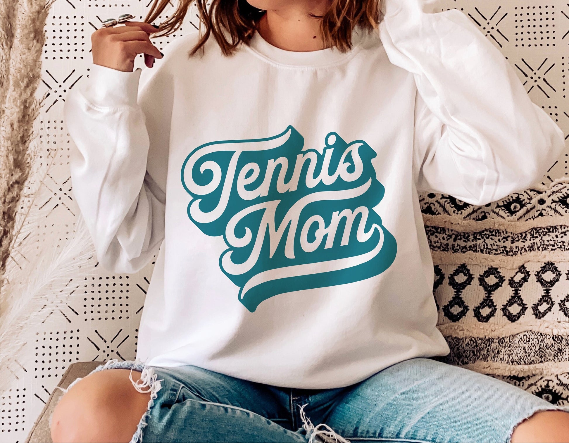 Woman wearing a white sweatshirt with 'Tennis Mom' design in teal, perfect for tennis fans and sporty mothers.