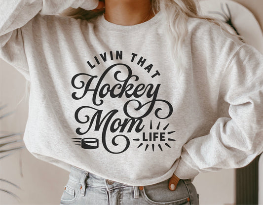 Woman wearing a sweatshirt with 'Livin That Hockey Mom Life' text design, ideal for Cricut and Silhouette projects.