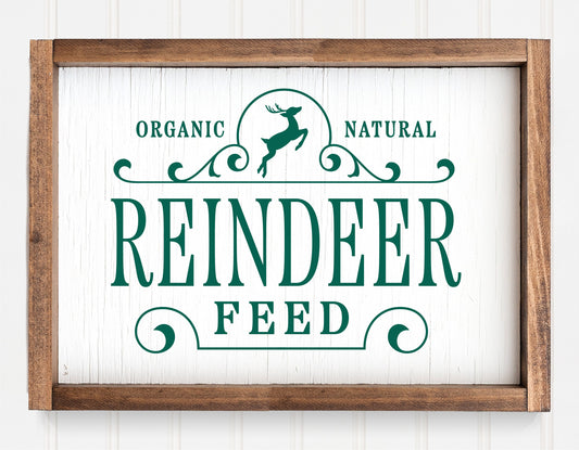 Rustic "Reindeer Feed" Christmas sign ornament with green lettering and wooden frame for holiday decor.