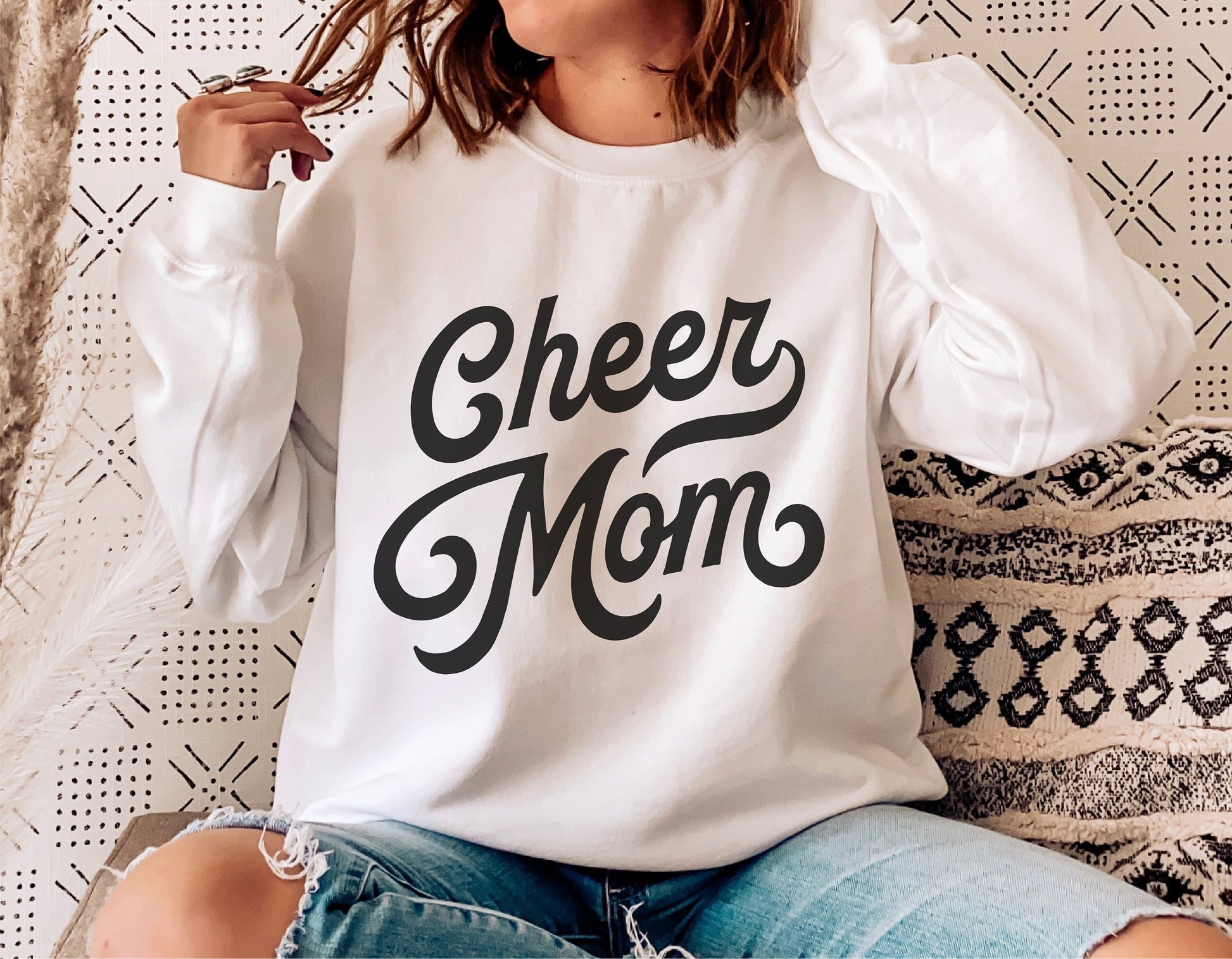 Woman in white sweatshirt with 'Cheer Mom' retro vintage lettering design, perfect for cheerleading enthusiasts and DIY projects.