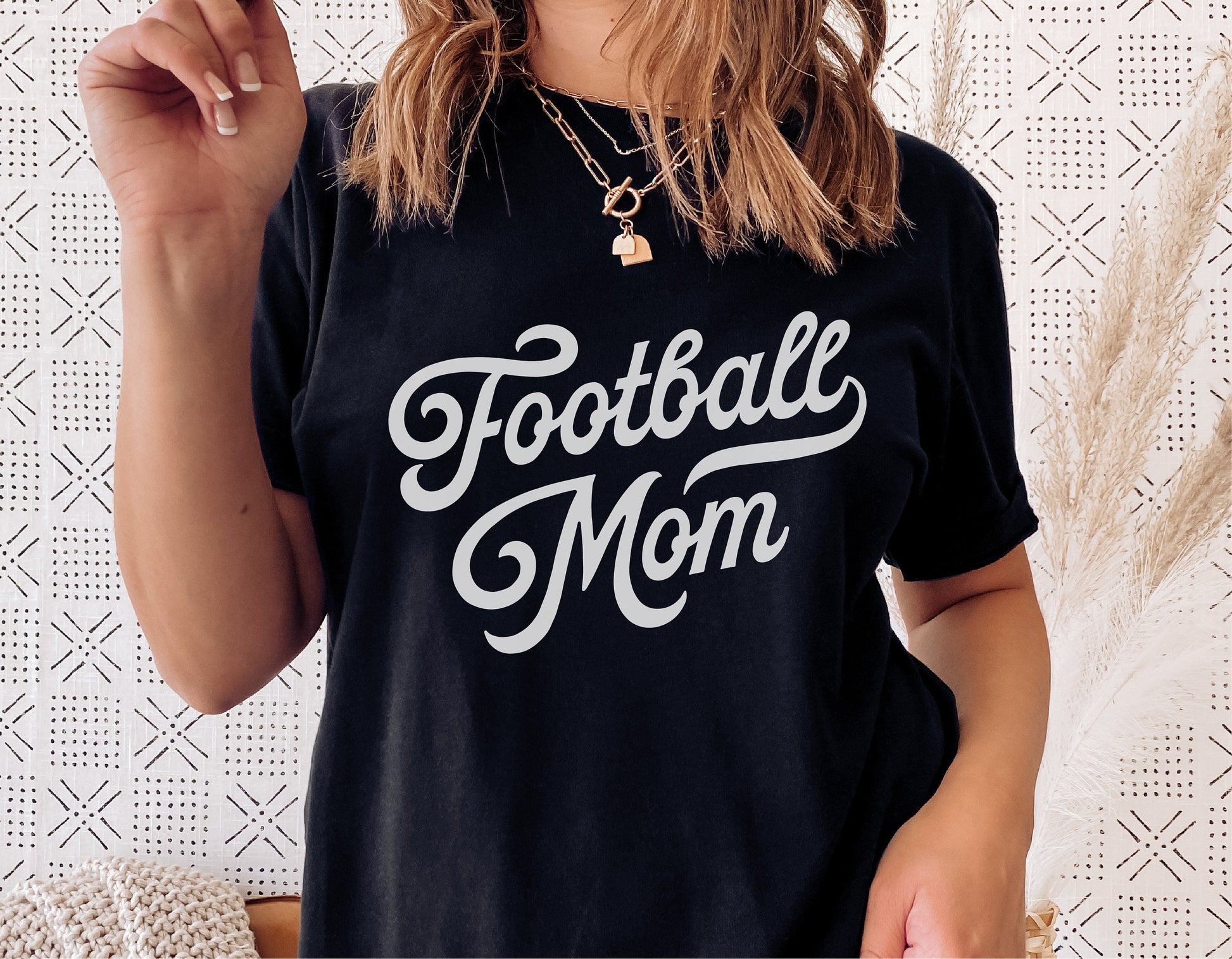 Woman wearing a black Football Mom shirt with vintage script design, ideal for sports fan SVG projects and digital cut files.