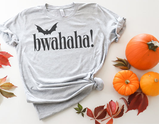 Gray Halloween t-shirt with 'bwahaha!' text and bat image, surrounded by pumpkins and autumn leaves.