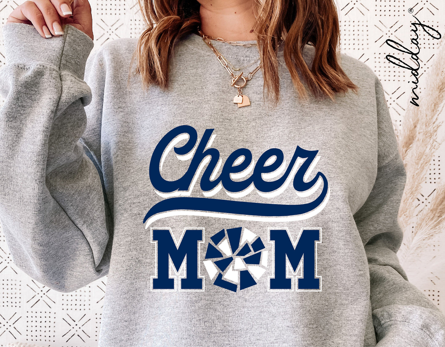Woman wearing grey sweatshirt with 'Cheer Mom' design featuring blue text and pom pom graphic, suitable for cheerleader SVG projects.
