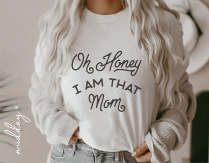 Woman wearing white sweater with 'Oh Honey I Am That Mom' text, fashion style, mom life shirt, casual apparel, cozy outfit inspiration