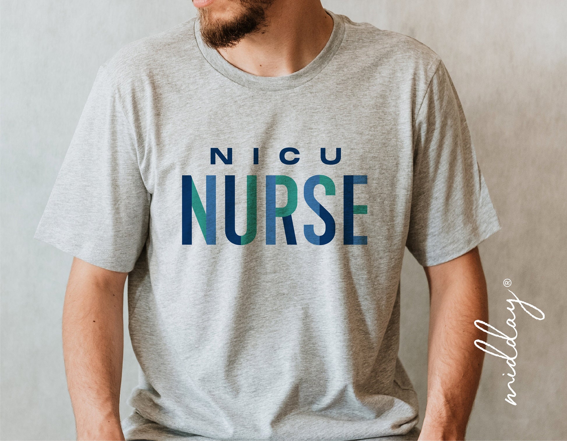 Gray t-shirt with 'NICU Nurse' text in blue and green, worn by a man sitting down.