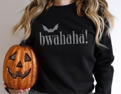 Person wearing black 'Bwahaha' Halloween shirt holding a glittery pumpkin.