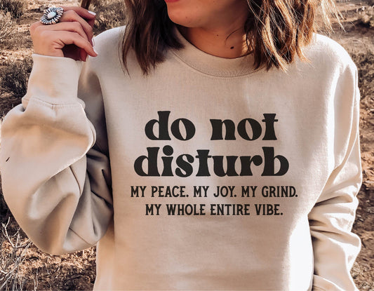 Woman wearing sweatshirt with 'do not disturb' funny quote, outdoor setting