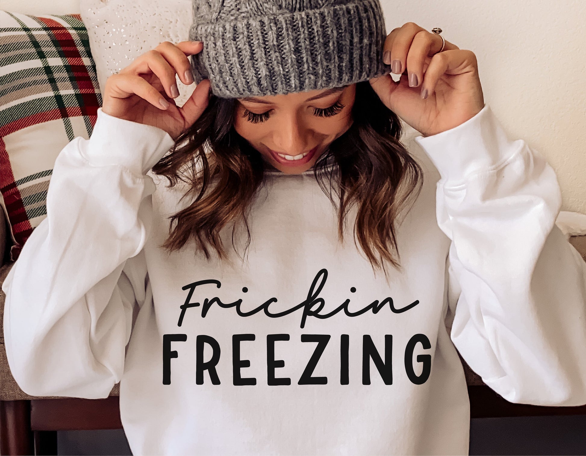 Woman wearing white sweatshirt with 'Frickin Freezing' design, winter fashion, cozy holiday wear.