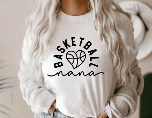 Woman wearing a white shirt with 'Basketball Nana' and heart design text, perfect for game day grandma or sports fan.
