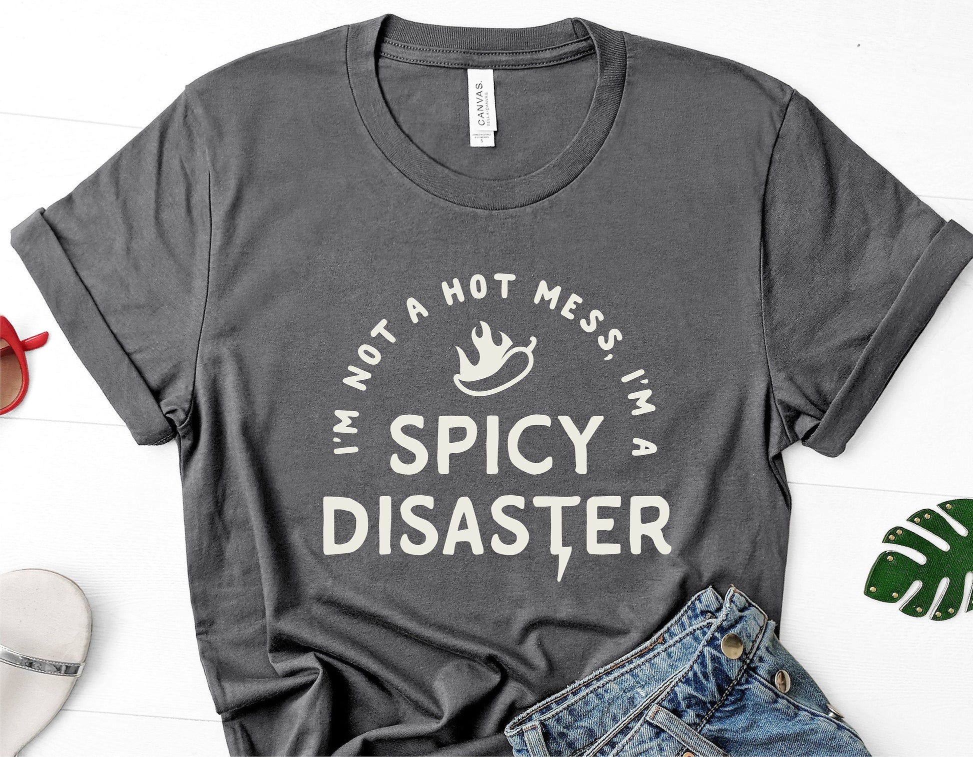 Gray t-shirt with 'I'm Not A Hot Mess, I'm A Spicy Disaster' text, perfect for sassy style lovers, humorous fashion statement.