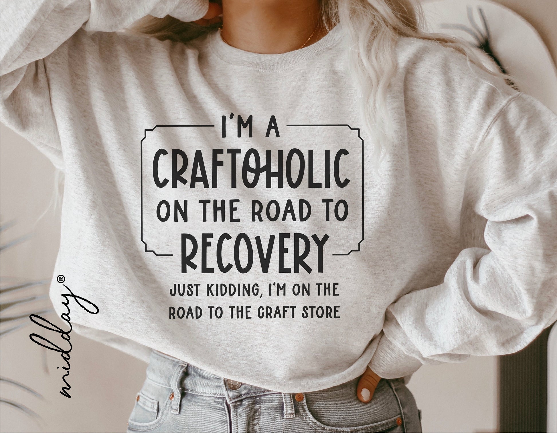 Woman wearing a sweatshirt with "I'm a Craftoholic on the Road to Recovery" print, humorous crafting design, casual setting.