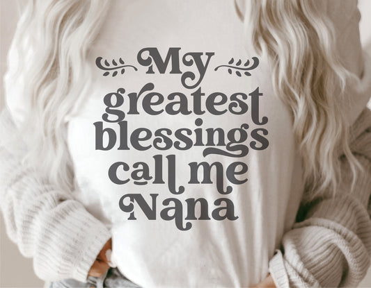 Woman wearing 'My Greatest Blessings Call Me Nana' shirt, ideal for Mother's Day gifts, featuring Cricut and Silhouette compatible design.