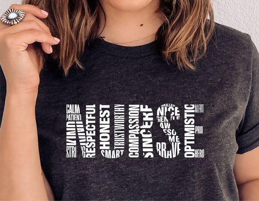 Woman wearing a black shirt with "Nurse" word art design featuring positive attributes like respectful, honest, and optimistic.