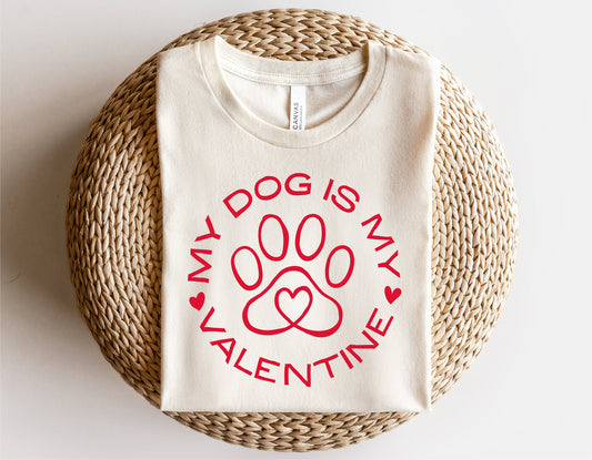 "My Dog Is My Valentine" shirt with red dog paw heart design, perfect for Valentine's Day, displayed on a woven mat.