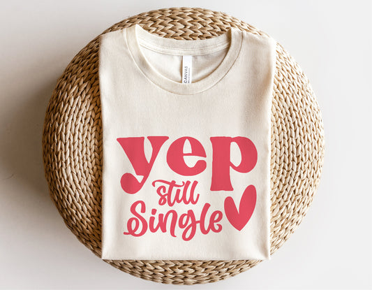 Cream t-shirt with 'Yep Still Single' in red text and heart design, funny Valentine's Day gift idea.