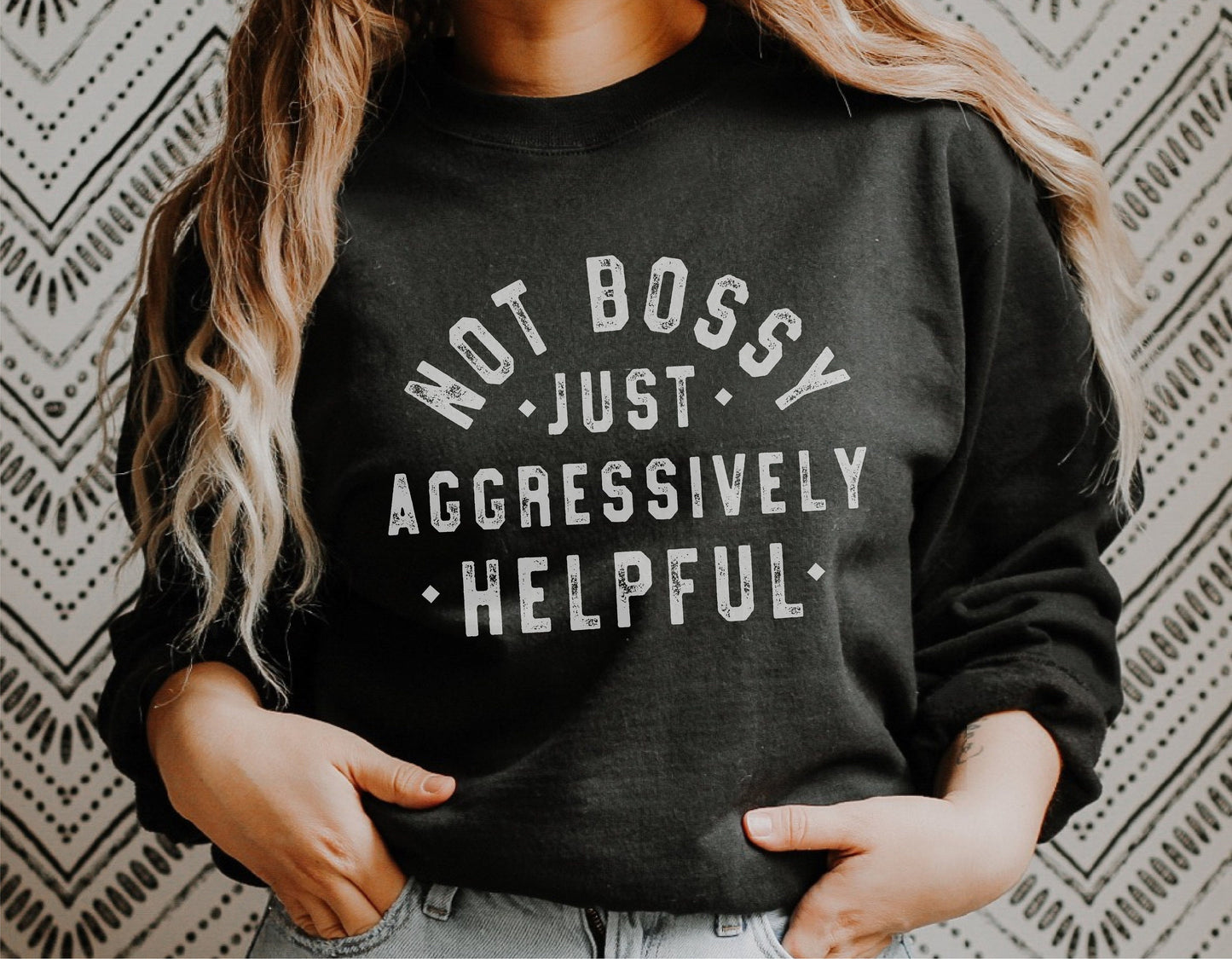 Woman wearing a black sweatshirt with 'Not Bossy Just Aggressively Helpful' text. Perfect for entrepreneurs and go-getters.