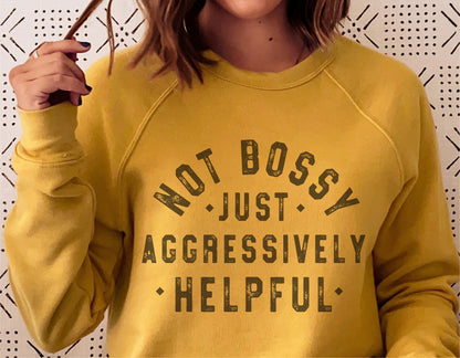 Woman wearing yellow sweatshirt with 'Not Bossy Just Aggressively Helpful' printed in bold letters.