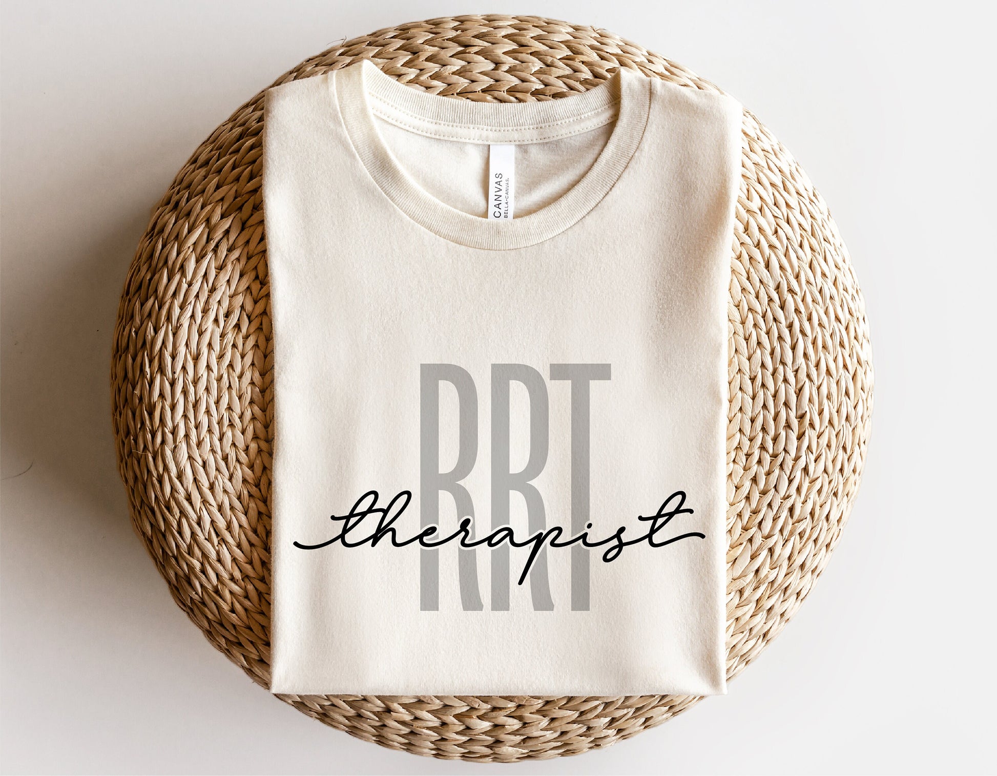 Beige t-shirt with 'RRT Therapist' design, perfect for Registered Respiratory Therapists, displayed on woven mat.