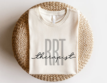 Beige t-shirt with 'RRT Therapist' design, perfect for Registered Respiratory Therapists, displayed on woven mat.