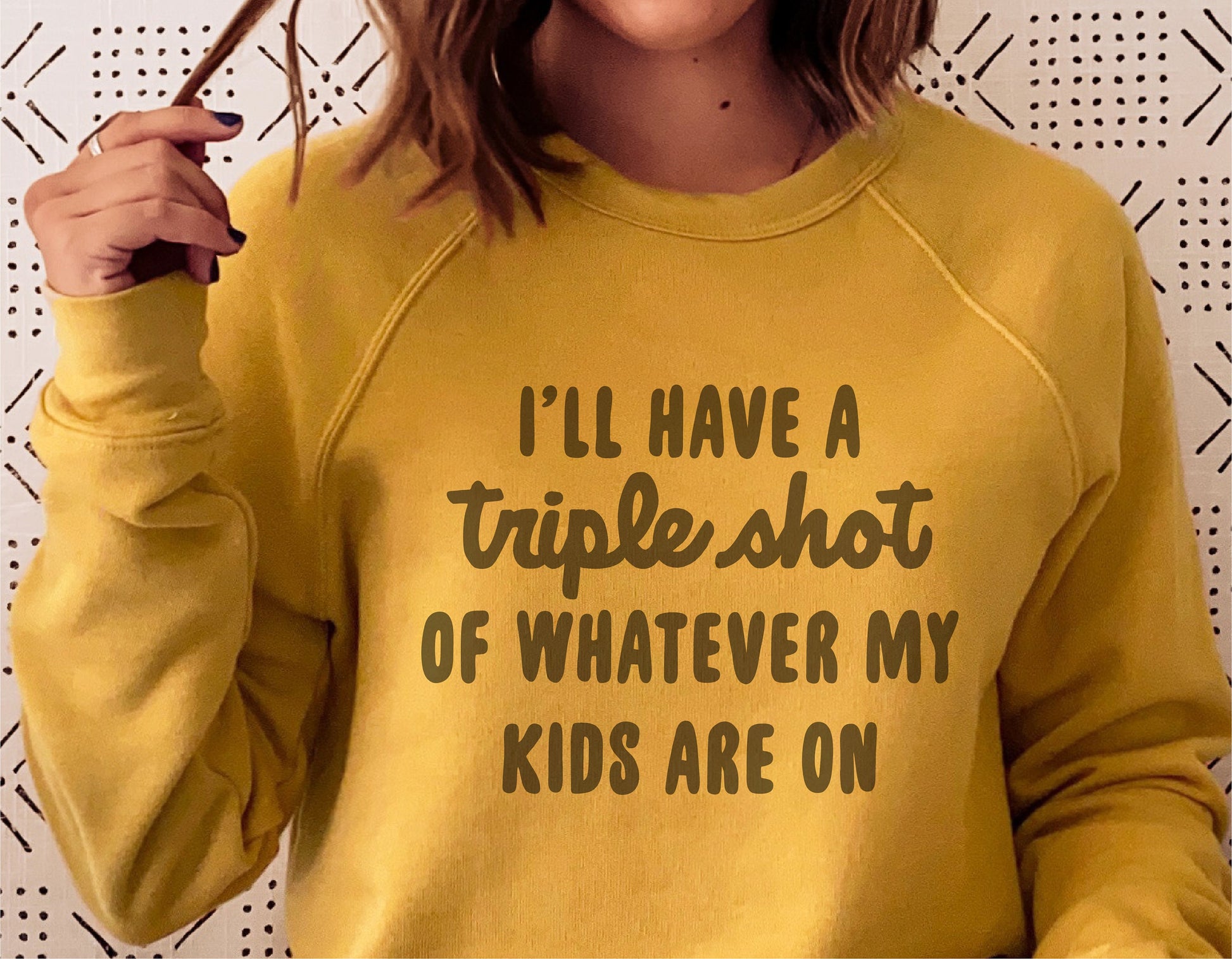 Woman wearing yellow sweatshirt with 'I'll have a triple shot of whatever my kids are on' text, funny mom apparel.