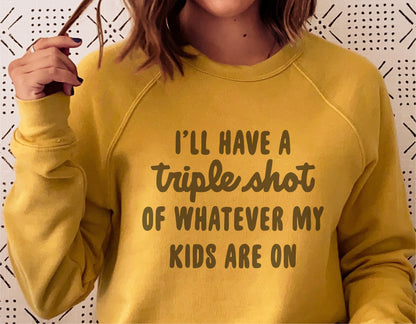 Woman wearing yellow sweatshirt with 'I'll have a triple shot of whatever my kids are on' text, funny mom apparel.