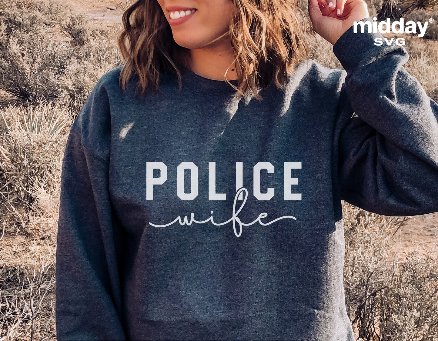Woman wearing a gray sweatshirt with 'Police Wife' text design in a natural outdoor setting.