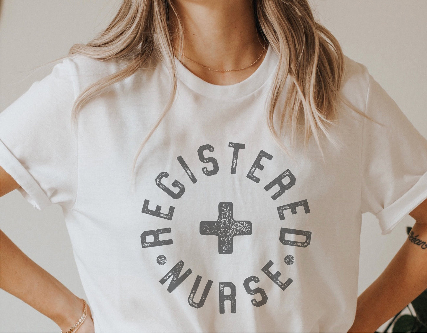 Woman wearing a white shirt with 'Registered Nurse' text and medical cross design, ideal for nursing apparel.