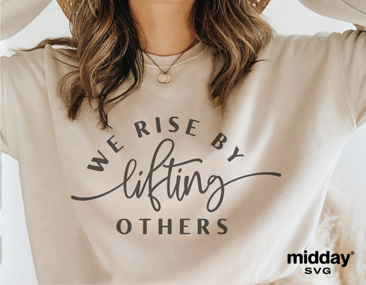 Woman wearing a beige shirt with 'We Rise By Lifting Others' quote in stylish lettering, part of kindness SVG collection.