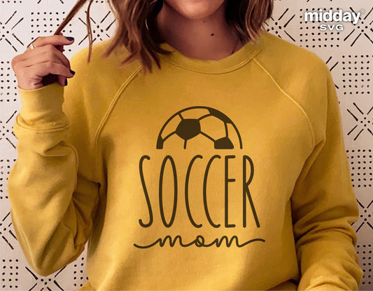 Person wearing a yellow sweatshirt with 'Soccer Mom' and soccer ball graphic designed for Cricut and Silhouette projects.