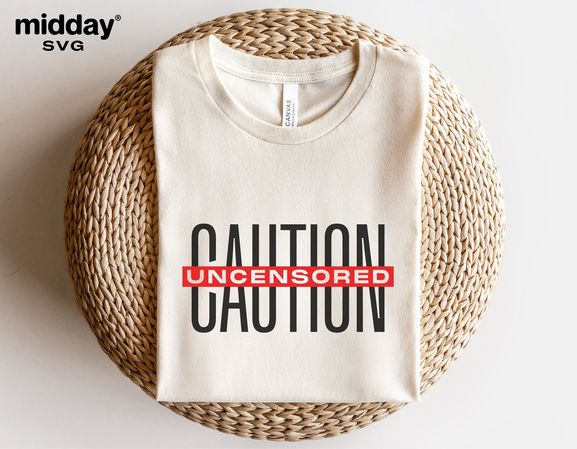 Caution Uncensored t-shirt folded, featuring a bold design, resting on a wicker surface. Ideal for Cricut and Silhouette crafting projects.